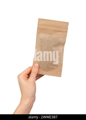 Hand holding small zip-lock kraft paper bag. Ziplock pouch, eco brown beige package, soft pack isolated on white background Stock Photo