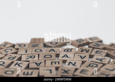 Wooden tiles with alphabet letters scattered on white background Stock Photo