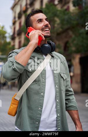 Cheerful man outdoors walking in the city speaking on the phone. Stock Photo