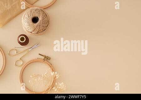 Creative vintage composition of sewing scissors, thread, jute, embroidery hoop, dry flowers and old crumpled paper on beige background with copy space Stock Photo