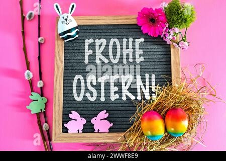 Augsburg, Bavaria, Germany - March 23, 2024: Happy Easter Greeting on a blackboard surrounded by Easter decorations with an Easter nest and colorful eggs. PHOTOMONTAGE *** Frohe Ostern Gruß auf einer Tafel umgeben von Osterdekoration mit Osternest und bunten Eiern. FOTOMONTAGE Stock Photo