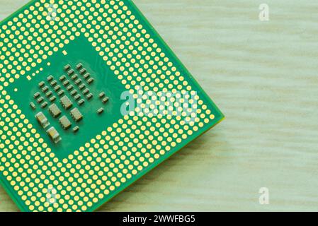 Bottom side of central processor unit (CPU) detailing the individual chips and gold connection pins on blurred wood grain table top Stock Photo