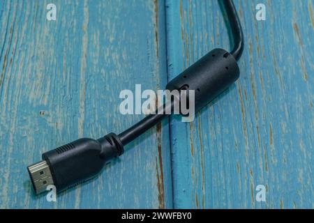 Black HDMI monitor cable isolated on blue wood grain background Stock Photo