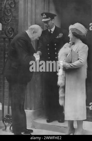 A photograph captures King George VI and Queen Elizabeth I being greeted by Winston Churchill at 10 Downing Street, London. Taken around 1940, this image highlights a significant moment of unity among Britain's leaders during the Second World War, showcasing the close collaboration between the monarchy and the government in guiding the nation through one of its darkest periods. Stock Photo