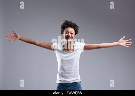 Beautiful young woman with afro hair laughs joyously, arms open wide. Life's beautiful, I inspire, welcome, include, says this dark-skinned girl. Whit Stock Photo