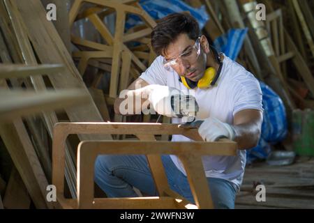 A man is focused as he shapes a piece of wood with his tools in a workshop setting. Stock Photo