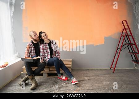 Happy family making repair in home. Young loving couple doing renovations in new house. Relaxed man and woman sitting on floor Stock Photo
