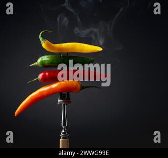 Hot chili peppers with smoke on a black background. Concept of spicy food. Stock Photo