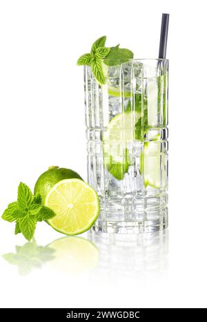 Mojito cocktail in tall crystal glass with drinking straw, lime and mint leaves isolated on white reflective surface. Stock Photo