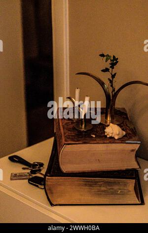 A rustic candle stand atop a stack of vintage books. Stock Photo