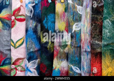 Abstract close-up detail of colorful, patterned wool scarves neatly hung on a display rack. Stock Photo