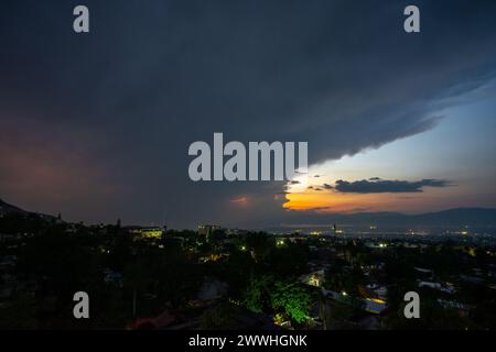 Lightning bolt falling over the city of Port-au-Prince, Haiti with dramatic clouds on one side and a colorful sunset on the other Stock Photo