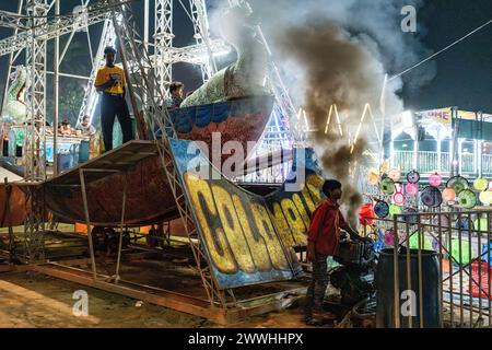 Smoke bellows from a an engine as revellers await the start of the fair ride in Kolkata, India Stock Photo