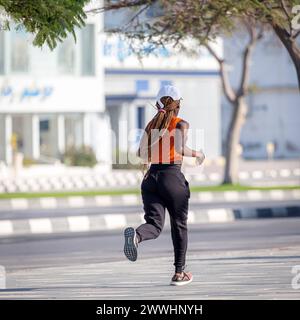 Ras Al Khaimah, UAE - February 5, 2022: African-american woman running on the street, active lifestyle Ras Al Khaimah, U Ras Al Khaimah, UAE - Februar Stock Photo