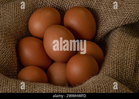 Fresh chicken eggs in a basket on a sack, egg day, wooden table.Selective focus Stock Photo
