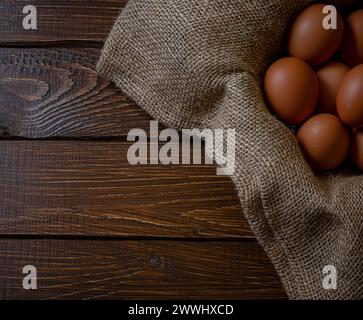 Fresh chicken eggs in a basket on a sack, egg day, wooden table.Selective focus Stock Photo