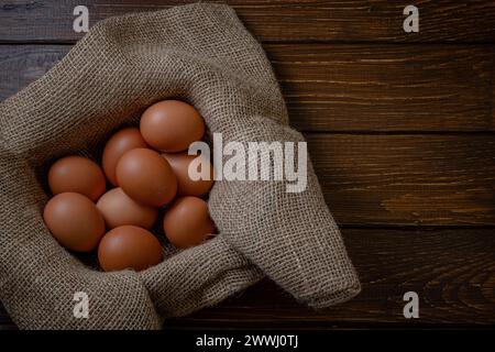 Fresh chicken eggs in a basket on a sack, egg day, wooden table.Selective focus Stock Photo