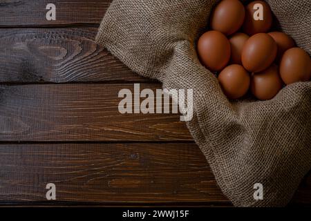 Fresh chicken eggs in a basket on a sack, egg day, wooden table.Selective focus Stock Photo