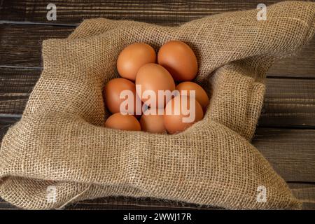 Fresh chicken eggs in a basket on a sack, egg day, wooden table.Selective focus Stock Photo