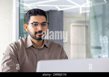 Focused Indian businessman using a laptop at his office workspace, embodying professionalism and dedication. Stock Photo