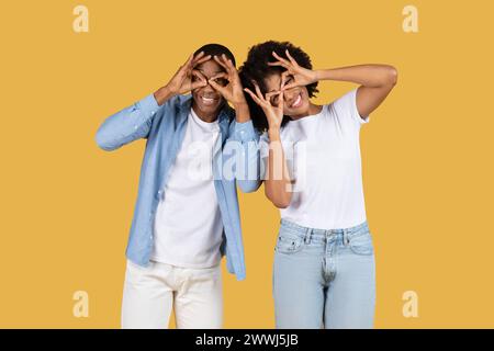Playful African American couple making funny faces with fingers imitating glasses Stock Photo