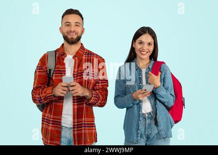 Boyfriend and girlfriend college students using cell phones, blue background Stock Photo