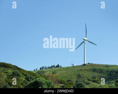Sustainable eco power energy concept. Modern wind turbine on green hilltop, generating clean renewable and pollution-free energy farm, Windmill genera Stock Photo