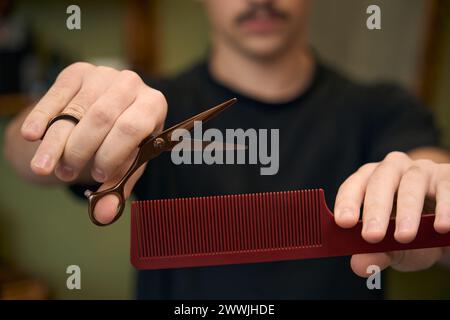 Blurred barber showing scissors and hairbrush Stock Photo