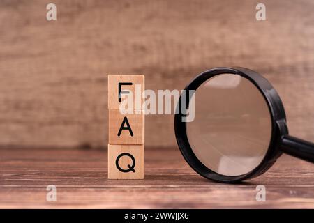 Faq word on wood block and magnifying glass Stock Photo