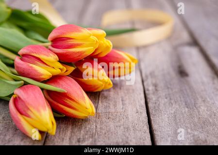 Bouquet of Orange-yellow tulips on the rustic wooden table with copy space for text. Selective focus. Stock Photo