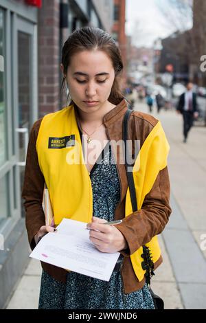 Young woman promoting Amnesty International New York City, USA. Young attractive and miling woman promoting Amnesty International in the streets of down town Brooklyn. MRYES New York City Down Town, Brooklyn New York United States of America Copyright: xGuidoxKoppesx Stock Photo
