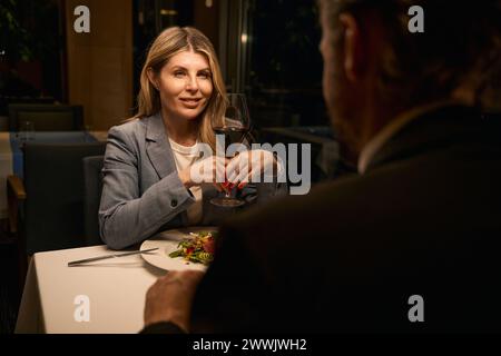 Smiling businesswoman communicates with a man over dinner in restaurant Stock Photo
