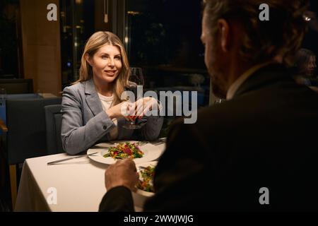 Middle-aged businesswoman communicates with a man over dinner in restaurant Stock Photo