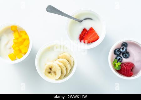 assortment of different yogurts with berries, fruits, mango and banana on white. healthy breakfast Stock Photo