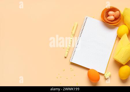 Blank notepad for recipes with pen, Easter eggs and baking molds on orange background Stock Photo