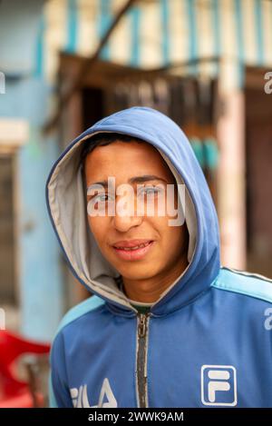 A young man in a hooded jacket smiles softly for a portrait, Bahariya, Egypt Stock Photo
