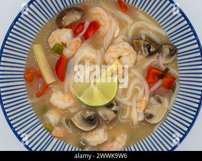 Indulge in a nutritious bowl of ramen noodle soup, boasting succulent shrimps, vibrant red peppers, fragrant lemongrass, and earthy mushrooms, present Stock Photo