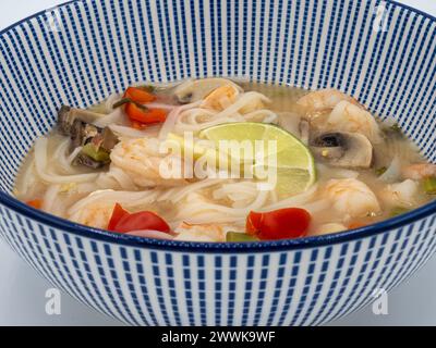 Indulge in a nutritious bowl of ramen noodle soup, boasting succulent shrimps, vibrant red peppers, fragrant lemongrass, and earthy mushrooms, present Stock Photo