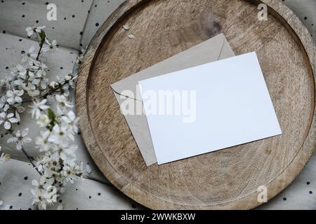 Spring still life composition. Blank greeting card mockup, craft envelope. Feminine styled photo. Floral scene. Blurred white cherry tree blossoms on Stock Photo