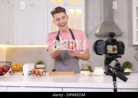 Smiling food blogger explaining something while recording video in kitchen Stock Photo