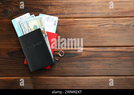 Honeymoon concept. Two golden rings, passports, money and tickets on wooden table, top view. Space for text Stock Photo