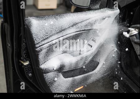 A man sprays cleaning foam on the interior of a car. Stock Photo