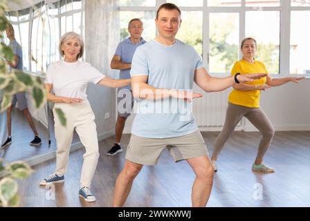 Positive instructor leading zumba class for seniors in fitness studio Stock Photo