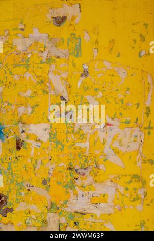 Old wall painted yellow with peeled-off paper advertisements leftovers. Stock Photo