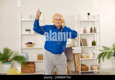 Happy senior man in headphones listening to music using smartphone Stock Photo