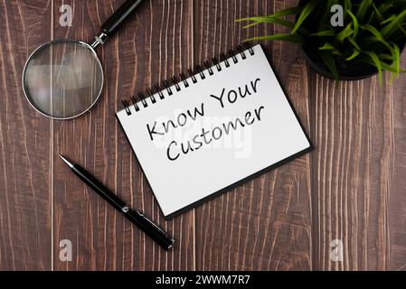 Magnifying glass and notepad with text know your customer Stock Photo
