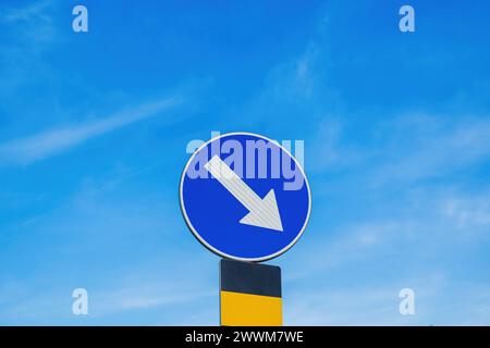 Mandatory carriageway keep right traffic sign in front of the roundabout, selective focus Stock Photo