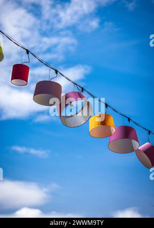 Blue sky background with clouds with colorful lampshade hanging from cable has free space top and bottom Stock Photo