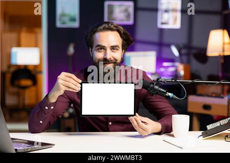 Portrait of smiling man in studio filming tech tutorial on how to do maintenance on mockup broken tablet. Online show host teaching subscribers how to open and fix isolated screen digital device Stock Photo