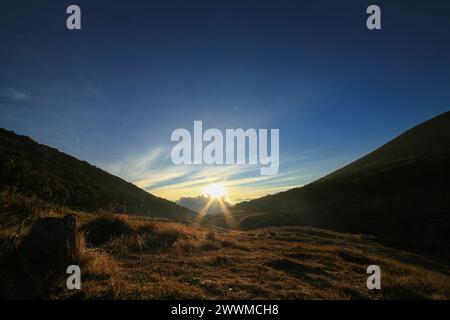 The sun shines from behind the hill Stock Photo